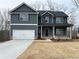 Two-story home boasts dark siding, white trim, covered porch, and a two-car garage with extended driveway at 5547 Bent Grass Way, Douglasville, GA 30135