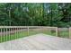 Wooden deck with wooden railings overlooking a green lawn and a wooded area beyond a fence at 700 Bayliss Dr, Marietta, GA 30068