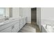 Bright bathroom featuring dual vanities, wood-style floor, and walk-in closet access at 6902 Winchester Pl, Fairburn, GA 30213