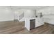 Open kitchen with island, stainless steel appliances, and adjacent stairs at 7758 Sheffield Ter, Fairburn, GA 30213