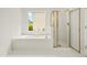 Bright main bathroom featuring a soaking tub and glass-enclosed shower and white tile at 3932 E Saddle Ridge Dr, Lithonia, GA 30038