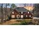 Beautiful brick home with a stately presence, framed by mature trees and a colorful sunset backdrop at 5679 Brookstone Nw Walk, Acworth, GA 30101