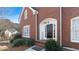 Elegant brick home entrance with a black front door, flanked by white trim and manicured shrubs at 5679 Brookstone Nw Walk, Acworth, GA 30101
