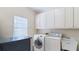 Laundry room with white washer and dryer, utility sink, window, and storage cabinets at 5679 Brookstone Nw Walk, Acworth, GA 30101