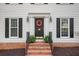 Close up of home entrance with red brick steps, front door wreath, and classic black sconces at 2828 Saddlebrook Nw Way, Marietta, GA 30064