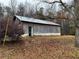 Exterior shot of a weathered barn with a metal roof and a single door on a wooded lot at 291 Folsom Glade Rd, Rydal, GA 30171