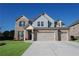 Inviting two-story brick home featuring a three-car garage and a well-manicured lawn at 2256 Cadenza Cir, Dacula, GA 30019