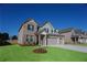 Two-story brick home with a three-car garage and a freshly planted tree in the front yard at 2256 Cadenza Cir, Dacula, GA 30019