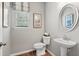 Well-lit powder room featuring a pedestal sink, toilet, mirror, and neutral wall color at 525 Lanier Way, Temple, GA 30179