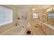 Bright bathroom featuring a soaking tub, neutral tile and decor, and a window for natural light at 3114 Superior Dr, Dacula, GA 30019