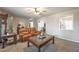 Inviting living room with neutral walls and carpet, featuring a large window, ceiling fan, and comfortable brown leather sofa at 504 Hanover Ct, Woodstock, GA 30188