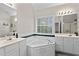 Main bathroom featuring double vanity sinks, a large soaking tub, and a window at 3130 Goldmist Dr, Buford, GA 30519