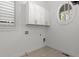 A bright laundry room with built-in cabinets, a round window, and tile flooring at 261 Thompson St, Alpharetta, GA 30009