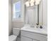 Powder room featuring white vanity, neutral walls, and a framed mirror and window at 1200 Primrose Park Rd, Sugar Hill, GA 30518