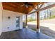Covered patio boasts exposed wood columns, brick siding, ceiling fan, and wooded backyard views at 1200 Primrose Park Rd, Sugar Hill, GA 30518