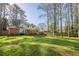 Expansive backyard featuring a lush lawn, mature trees, deck, and playground at 2736 Old Norcross Rd, Tucker, GA 30084