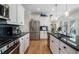 Well-lit kitchen with white cabinets, black countertops, stainless steel appliances, and a functional layout at 3470 Serenade Nw Commons, Kennesaw, GA 30152