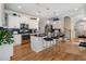 Open kitchen with white cabinets, black countertops, stainless appliances, an island with bar seating, and hardwood floors at 3470 Serenade Nw Commons, Kennesaw, GA 30152