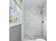 Updated walk-in shower with white marble-like tiles, modern fixtures, and a bright window at 2235 Chamois Ct, Decatur, GA 30035
