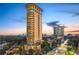 Building exterior with expansive balconies overlooking the city skyline and lush trees at dusk at 2881 Peachtree Ne Rd # 704, Atlanta, GA 30305