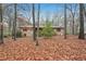 Back view of brick home with mature trees and ground covered in fallen leaves at 357 Forest Lake Rd, Lawrenceville, GA 30046