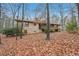 Backyard view of home with mature trees, deck, and brick exterior, surrounded by fallen leaves at 357 Forest Lake Rd, Lawrenceville, GA 30046