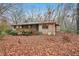 Back view of brick home with deck, surrounded by ground covered in fallen leaves at 357 Forest Lake Rd, Lawrenceville, GA 30046