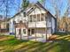 Back exterior with deck, enclosed porch, and stone chimney, complemented by a green lawn and wooded backdrop at 4013 Brenteresa Ct, Snellville, GA 30039