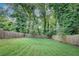 Spacious backyard with lush green grass, surrounded by a wooden fence and mature trees at 833 N Grand Nw Ave, Atlanta, GA 30318