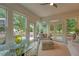 Bright sunroom with large windows, offering plenty of natural light and backyard views with a seating area and table at 155 Oakpark Ct, Mcdonough, GA 30253