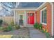 Inviting front porch with a red door, brick facade, and blossoming spring flowers at 245 Dennis Dr, Alpharetta, GA 30009