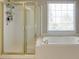 This is a bright bathroom with a glass shower and separate tub located near a bright window at 5446 Oxford Chase Way, Dunwoody, GA 30338