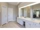 Bathroom with a double sink vanity and a large mirror, with a doorway view of an adjacent room at 5446 Oxford Chase Way, Dunwoody, GA 30338