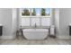 A white, free-standing bathtub sits beneath a window offering natural light in this modern bathroom at 574 Boulevard Ne Pl # 5, Atlanta, GA 30308