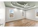 Bright bedroom featuring hardwood floors, three windows, ceiling fan, and decorative tray ceiling at 8160 Stone Hill Rd, Cumming, GA 30028