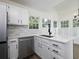 This bright kitchen features white cabinets, quartz countertops, stainless steel appliances, and a garden view at 53 Carrington Lndg, Douglasville, GA 30134