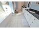 Bright bathroom featuring tile floors, white cabinets with a dark countertop, and a soaking tub at 8340 Nolandwood Ln, Villa Rica, GA 30180