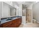 This bathroom features double sinks, cherry cabinets, a large mirror, a stand-alone shower, and ceramic tile flooring at 11 Perimeter E Ctr # 1115, Atlanta, GA 30346