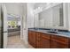 Bright bathroom with a double sink vanity, wooden cabinets, and a view into the Primary bedroom at 11 Perimeter E Ctr # 1115, Atlanta, GA 30346