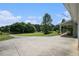 Large concrete driveway next to covered porch overlooking a picturesque yard with mature trees and greenery at 410 Bowen Ne Rd, White, GA 30184