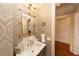 Elegant half bathroom featuring designer wallpaper, marble countertops, and gold faucet at 12710 Old Surrey Pl, Roswell, GA 30075