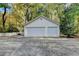 Detached two-car garage with white siding, set amidst a backdrop of lush greenery at 7185 Peachtree Dunwoody Rd, Atlanta, GA 30328