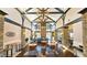 Interior of a well-lit lounge with high ceilings, stone columns, wooden tables, chairs, and a fireplace at 3699 Ashford Creek Ne Hl, Atlanta, GA 30319