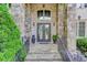 Elegant front entrance with stone accents, ornate iron doors, and meticulously landscaped surroundings at 2400 Weber Heights Way, Buford, GA 30519