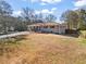 Exterior view of a charming single-story home with a large front yard and a mix of mature trees and open space at 4493 Old Hiram Lithia Spgs Rd, Powder Springs, GA 30127
