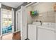 Efficient laundry room setup with a washer, dryer, shelving, and a view of the screened-in porch at 4493 Old Hiram Lithia Spgs Rd, Powder Springs, GA 30127