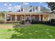 Inviting brick home featuring a manicured front lawn, covered porch with columns, and dormer windows at 320 Morganshire Pl, Atlanta, GA 30350