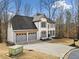 Traditional two-story home with gray-painted three-car garage, neutral siding and black mulch flower beds at 327 Horseshoe Bend Bnd, Woodstock, GA 30189