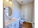 Half bathroom featuring decorative mirror, modern vanity, and wood-look tile flooring at 3780 Baxley Pine Trl, Suwanee, GA 30024