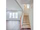 Carpeted staircase with wood banister and views to living area with luxury vinyl plank flooring at 3780 Baxley Pine Trl, Suwanee, GA 30024